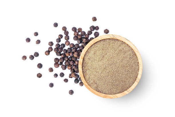 Ground pepper in wooden bowl and black peppercorns isolated on white background. Top view, flat lay.